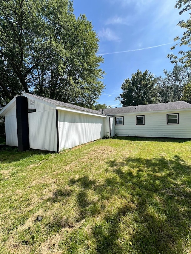 rear view of property featuring a yard and an outbuilding