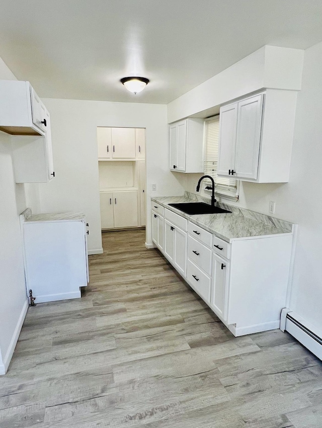 kitchen featuring light hardwood / wood-style floors, sink, white cabinetry, and a baseboard heating unit