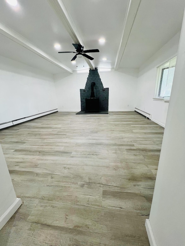 unfurnished living room with a wood stove, ceiling fan, and baseboard heating