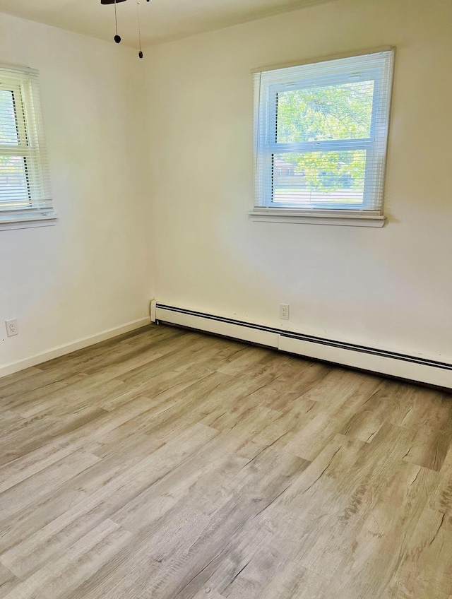 unfurnished room with a baseboard radiator and light hardwood / wood-style floors