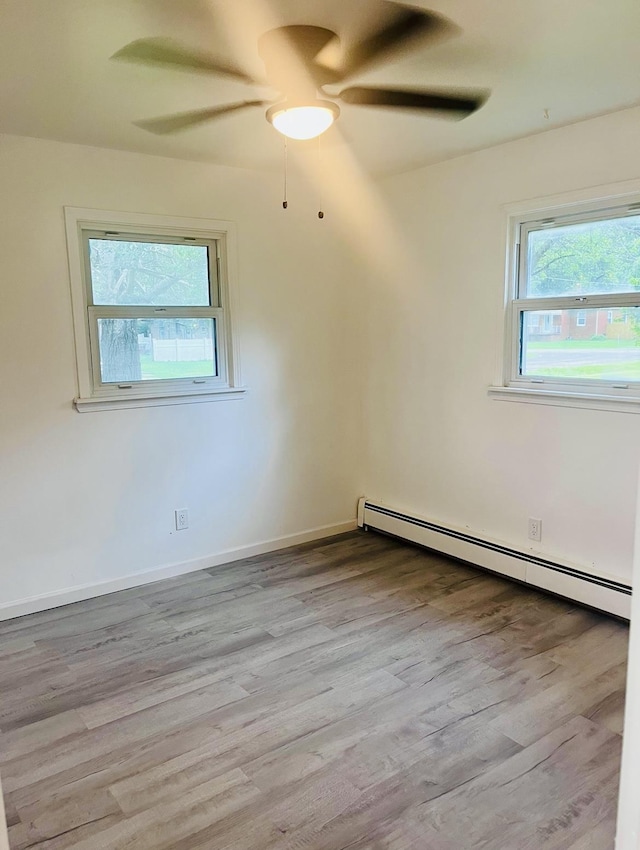 unfurnished room with light hardwood / wood-style flooring, a baseboard radiator, and plenty of natural light