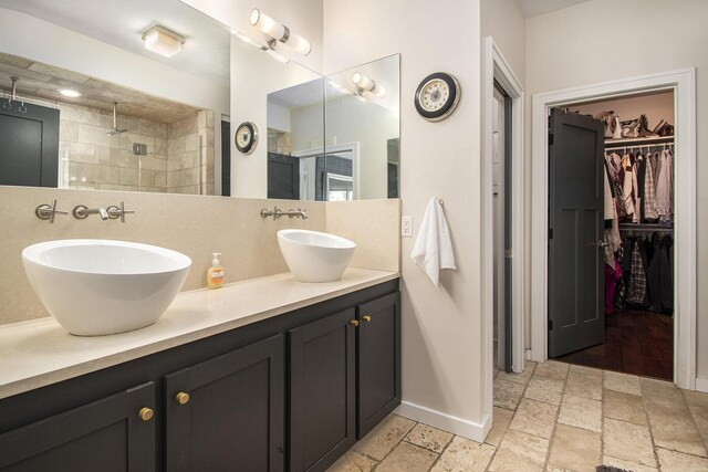 6248 Dublin Dr, Stanwood, MI 49346 - full bath with double vanity, stone tile flooring, a walk in closet, walk in shower, and baseboards