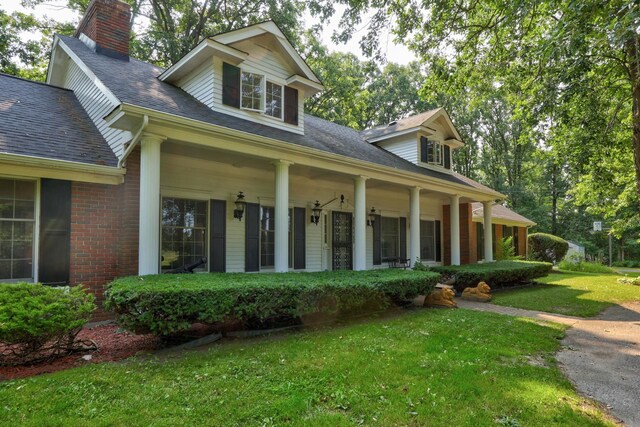 4705 Weiss Rd, Frankenmuth, MI 48734 - view of front facade with a chimney, a front yard, covered porch, and a shingled roof