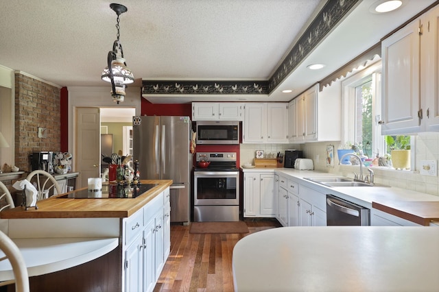 kitchen featuring butcher block counters, white cabinetry, stainless steel appliances, and decorative light fixtures