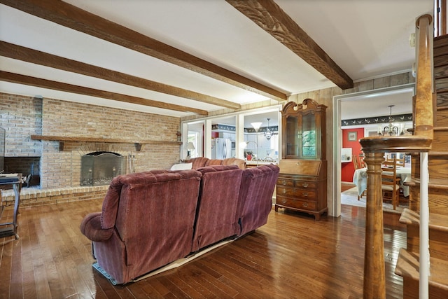 living room featuring beamed ceiling, dark hardwood / wood-style flooring, a brick fireplace, and brick wall