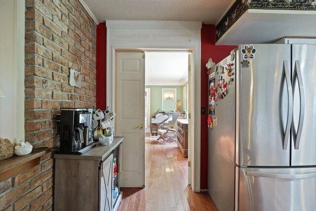 4705 Weiss Rd, Frankenmuth, MI 48734 - kitchen featuring freestanding refrigerator, ornamental molding, light wood-type flooring, and brick wall