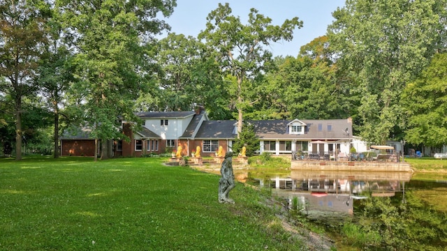 rear view of house with a water view and a lawn