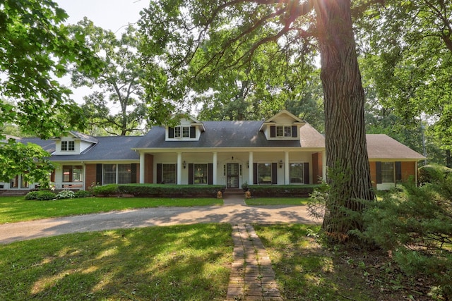 cape cod-style house featuring covered porch and a front lawn