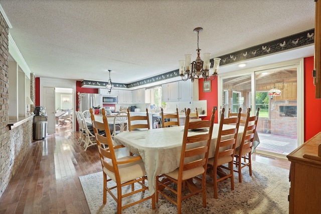 dining room featuring a chandelier, wood-type flooring, a textured ceiling, and a healthy amount of sunlight