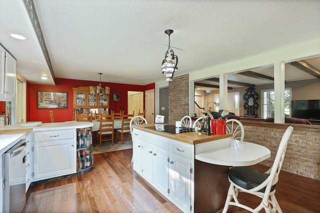 kitchen with dishwasher, decorative light fixtures, light hardwood / wood-style floors, a kitchen bar, and white cabinetry