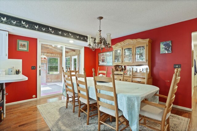 4705 Weiss Rd, Frankenmuth, MI 48734 - dining space featuring wood finished floors, a chandelier, a textured ceiling, and baseboards