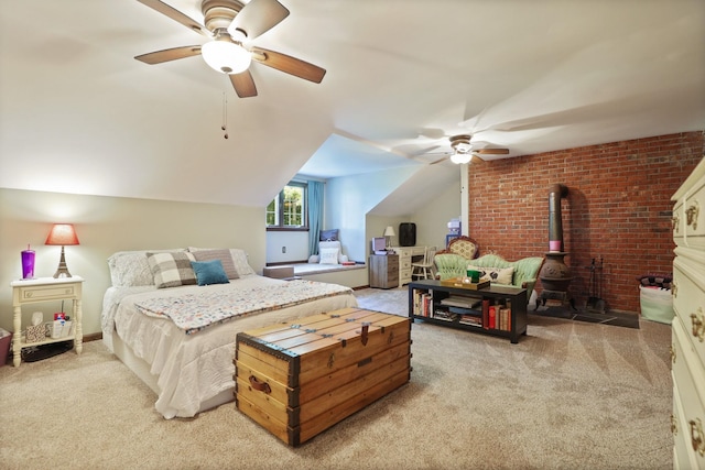 carpeted bedroom featuring ceiling fan, a wood stove, brick wall, and vaulted ceiling