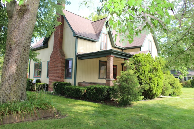 view of side of property with a porch and a lawn