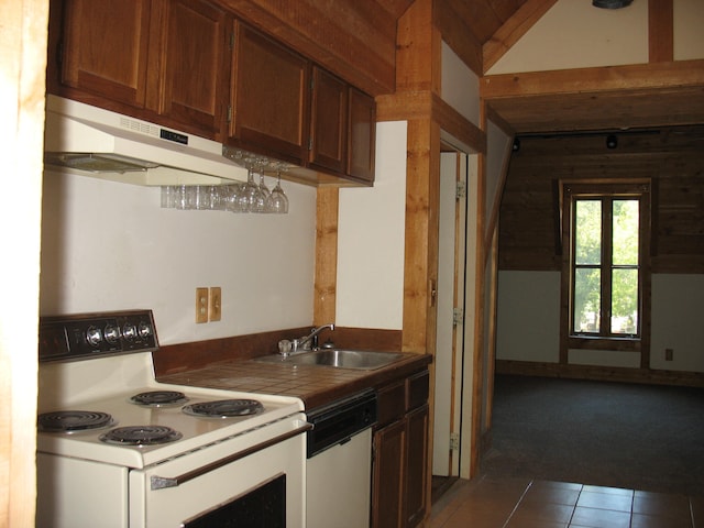 kitchen with sink, dark tile patterned floors, tile countertops, lofted ceiling, and white appliances