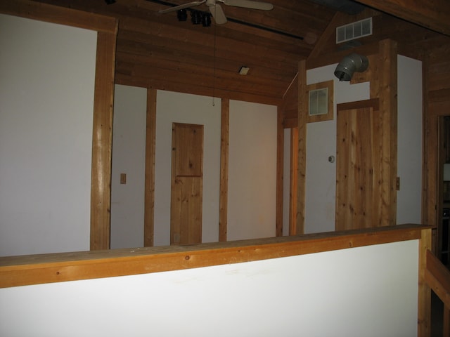 stairway with vaulted ceiling, ceiling fan, and wooden walls