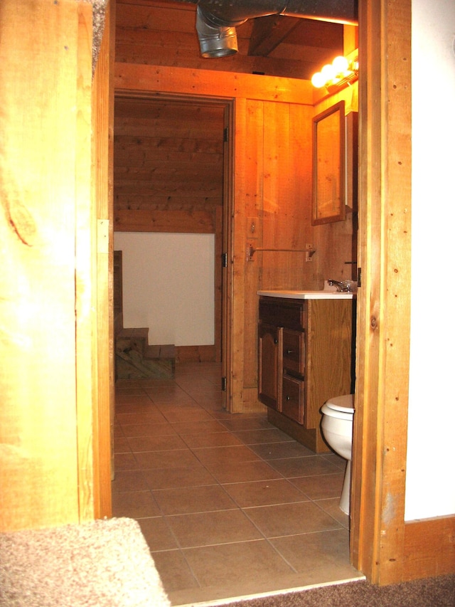 bathroom featuring wood walls, tile patterned flooring, vanity, and toilet