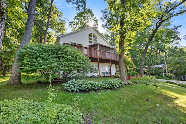 rear view of house featuring a wooden deck and a lawn