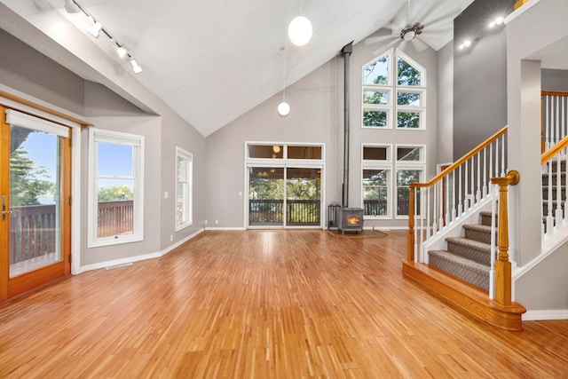 unfurnished living room featuring hardwood / wood-style floors, rail lighting, high vaulted ceiling, and ceiling fan