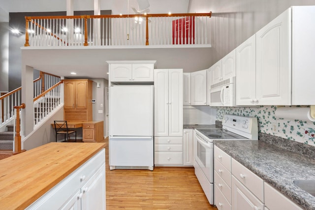 kitchen with white appliances, light hardwood / wood-style floors, white cabinetry, and tasteful backsplash