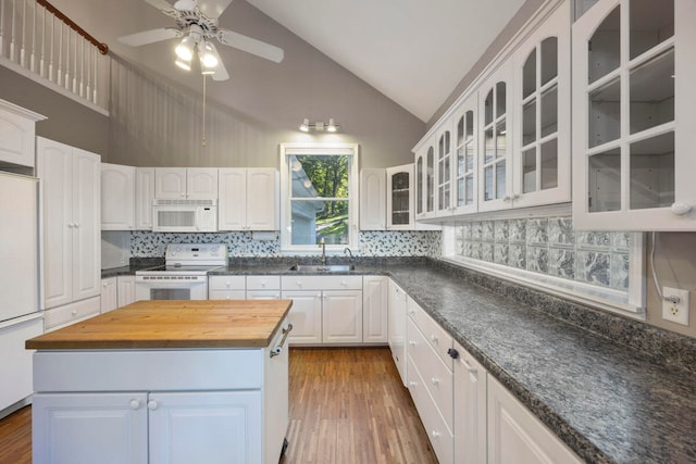 kitchen featuring white appliances, dark wood-type flooring, sink, a kitchen island, and white cabinetry