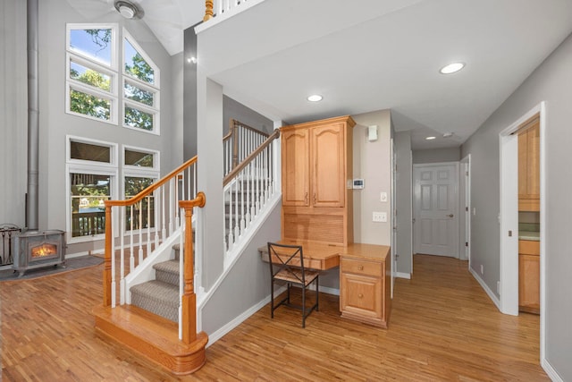 staircase featuring hardwood / wood-style floors, built in desk, and a wood stove