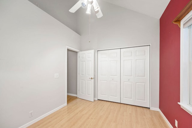 unfurnished bedroom featuring high vaulted ceiling, a closet, light hardwood / wood-style flooring, and ceiling fan