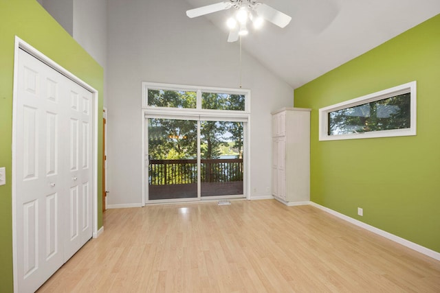 unfurnished bedroom featuring access to outside, high vaulted ceiling, ceiling fan, light hardwood / wood-style floors, and a closet