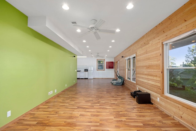 interior space with wood walls, a healthy amount of sunlight, and light wood-type flooring