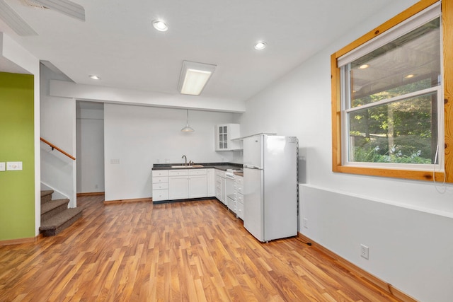 kitchen with white cabinets, white fridge, hanging light fixtures, and light hardwood / wood-style floors