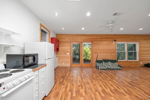 kitchen with light hardwood / wood-style floors, white range with electric cooktop, ceiling fan, and wood walls