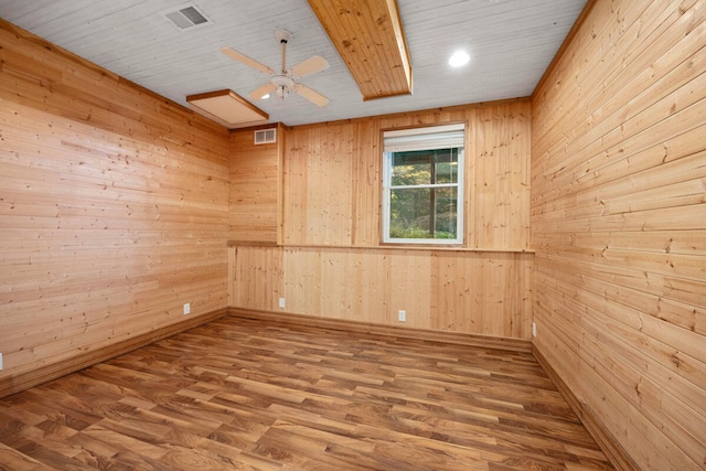 spare room featuring wood walls, ceiling fan, and wood-type flooring