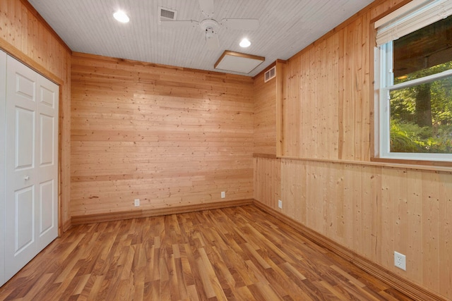 empty room featuring hardwood / wood-style flooring, ceiling fan, and wooden walls