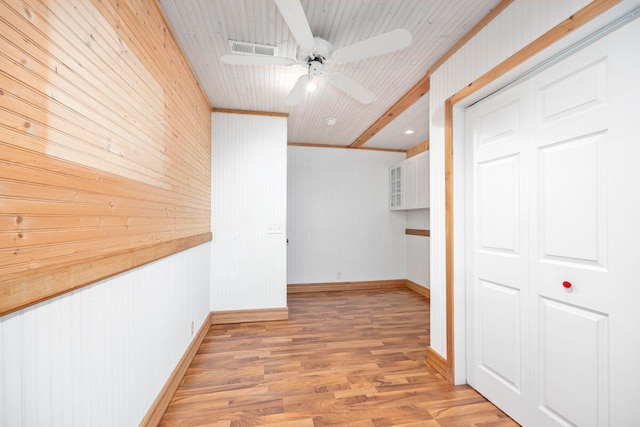 hallway with hardwood / wood-style floors, ornamental molding, and wood walls