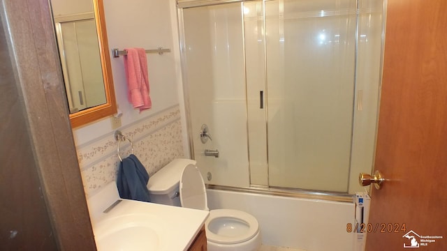 full bathroom featuring toilet, combined bath / shower with glass door, and vanity