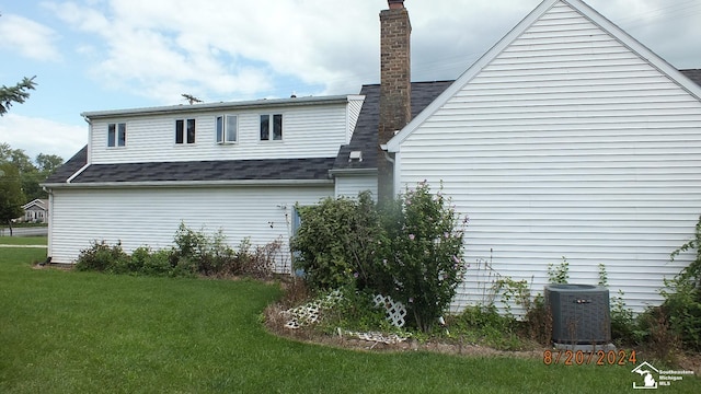 view of side of home with central AC and a yard