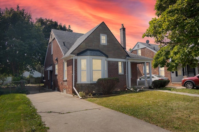 bungalow with brick siding, a front lawn, a chimney, and fence