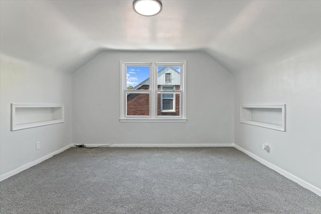 additional living space featuring carpet flooring, built in features, and vaulted ceiling