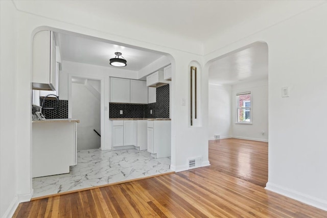 kitchen featuring backsplash, white cabinetry, and light hardwood / wood-style flooring