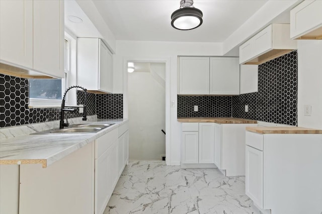 kitchen featuring white cabinets, backsplash, and sink