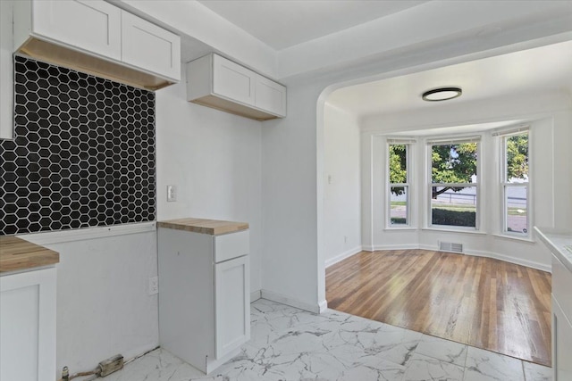 kitchen featuring butcher block counters, light hardwood / wood-style flooring, and white cabinets