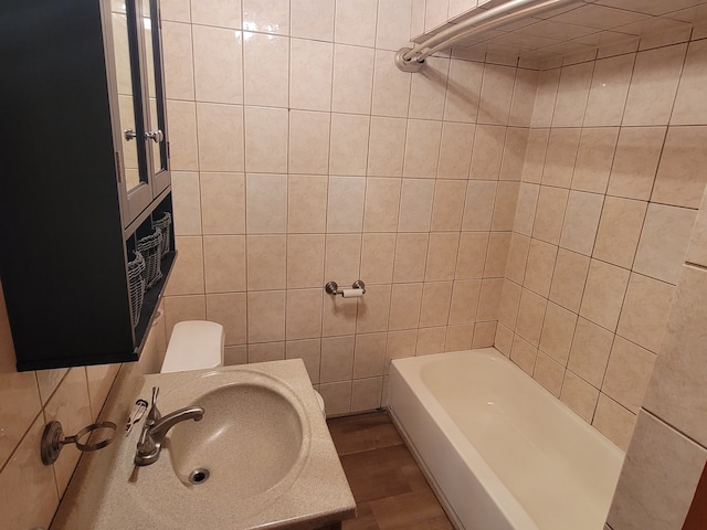 bathroom featuring hardwood / wood-style flooring, toilet, sink, and tile walls