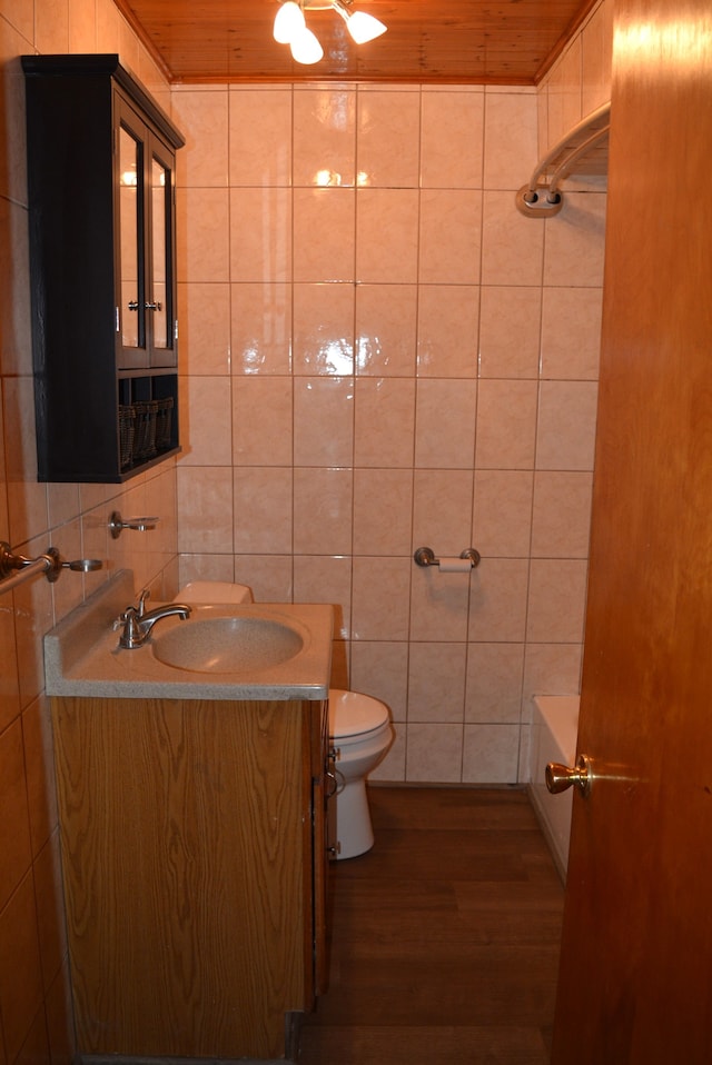 bathroom featuring toilet, vanity, tile walls, and hardwood / wood-style flooring