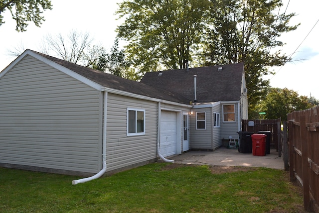 back of property featuring a patio, a yard, and a garage