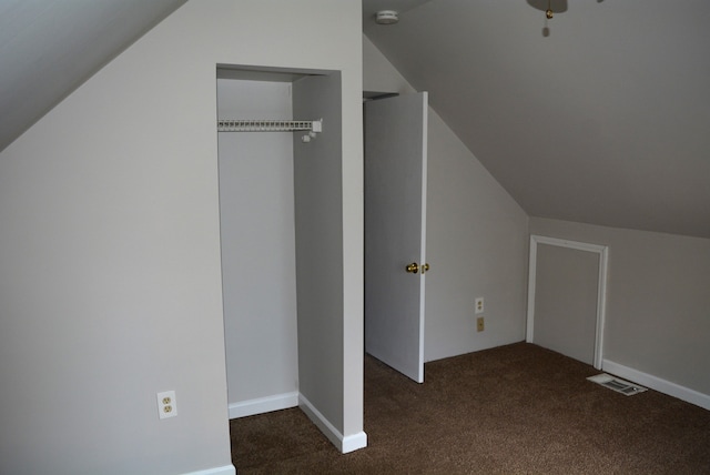 additional living space with dark carpet and lofted ceiling