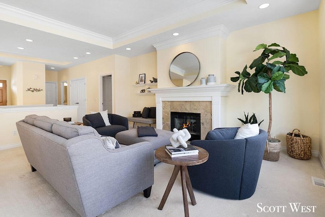 living room with ornamental molding, light colored carpet, a tile fireplace, and a raised ceiling