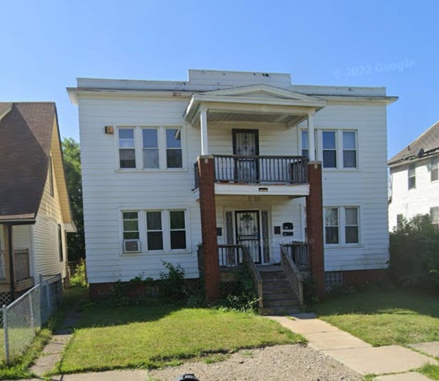 view of front of home with a porch, a balcony, and a front lawn