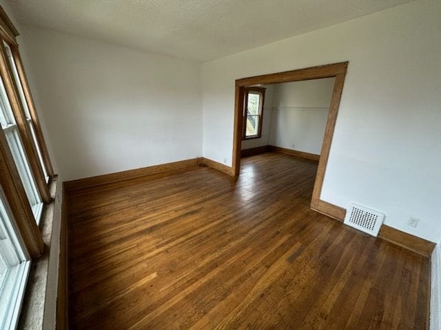 spare room with dark hardwood / wood-style floors and a textured ceiling