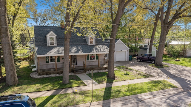 cape cod-style house featuring covered porch, an outbuilding, a garage, and a front lawn