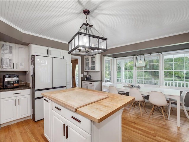 kitchen featuring light hardwood / wood-style flooring, white cabinets, a center island, white fridge, and hanging light fixtures