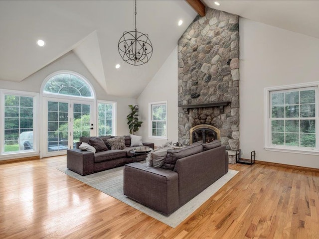 living room featuring high vaulted ceiling, a stone fireplace, beam ceiling, a notable chandelier, and light hardwood / wood-style floors